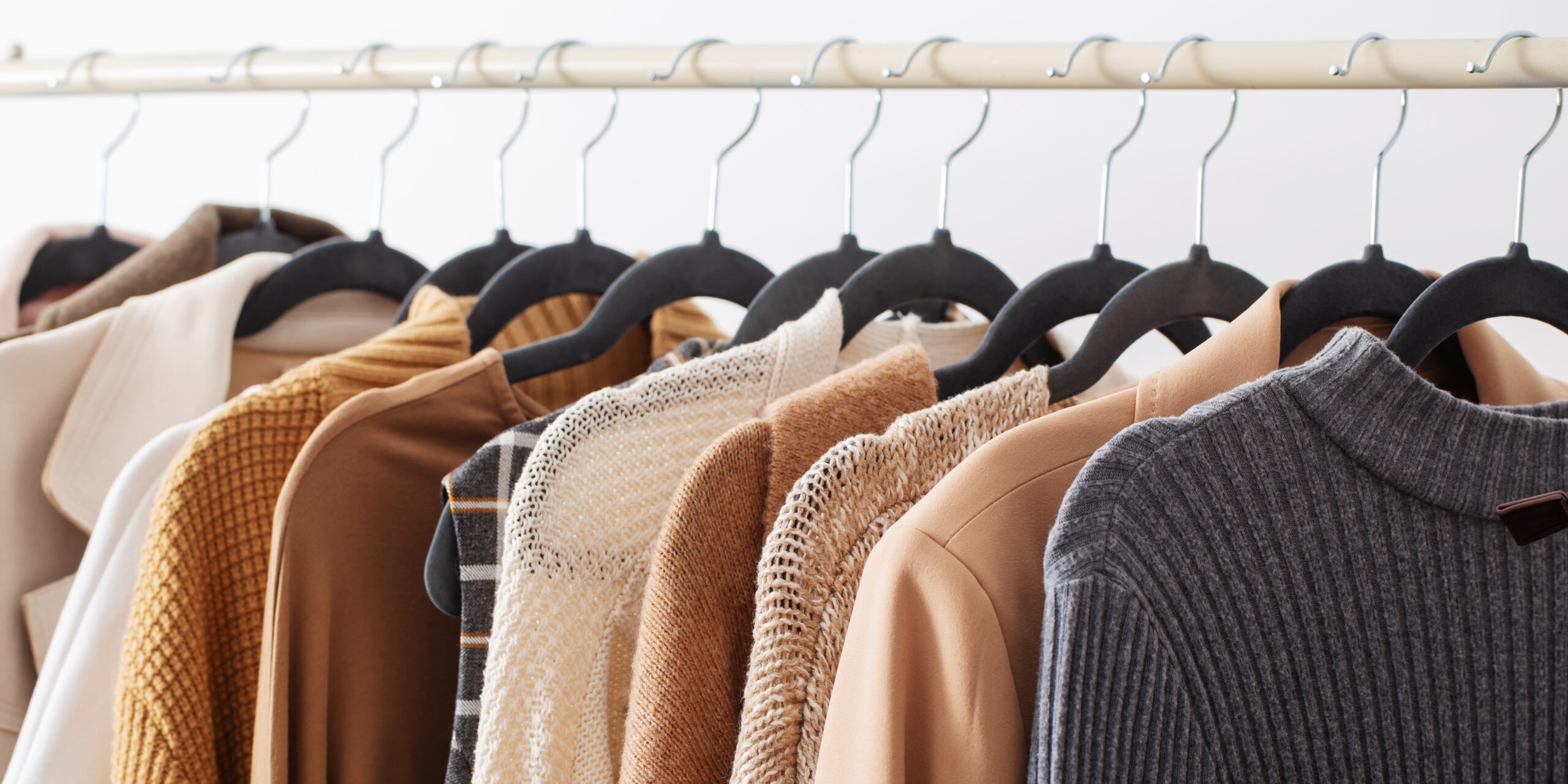 female autumn clothes on hangers in white room